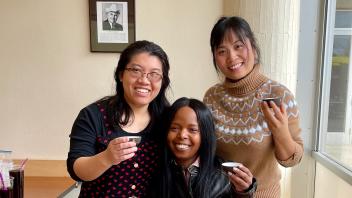 A group of three people smiling, holding tea cups