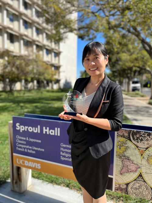 Professor Jiao Li holding an award outside Sproul hall