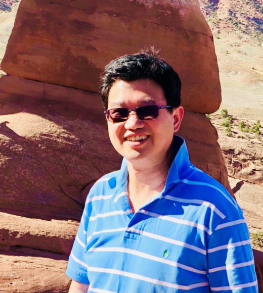 Man in striped shirt in front of a rock formation