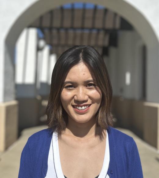A photo of a woman with an outdoor arch behind her.