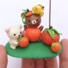a dough figurine of bears with pumpkins being held in a hand.